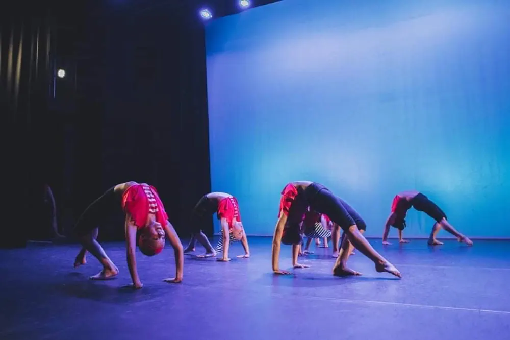 Acro dancers in a bridge on a blue-lit stage