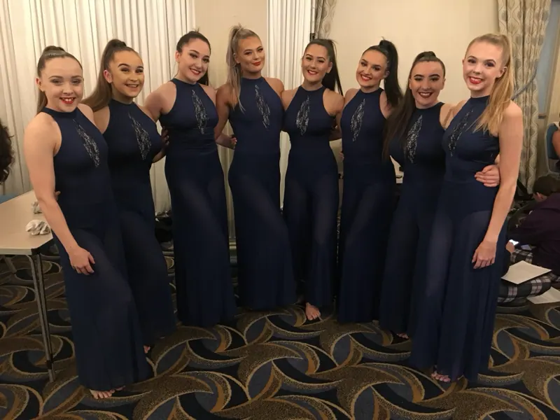 Senior dancers together in matching navy outfits